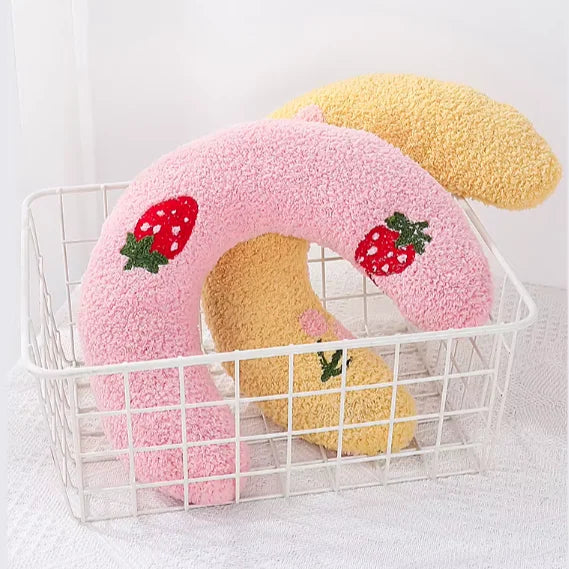 Coussins CozyU rose et jaune en forme de U avec motifs brodés présentés dans un panier – Oaura